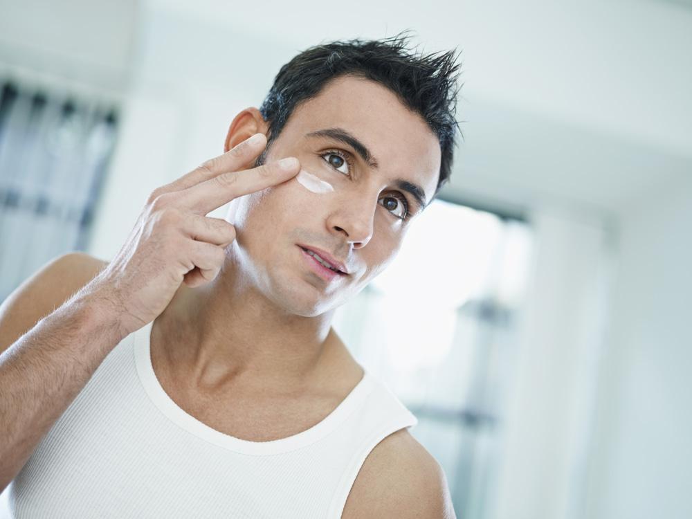 man using eye cream to treat dark circles in men