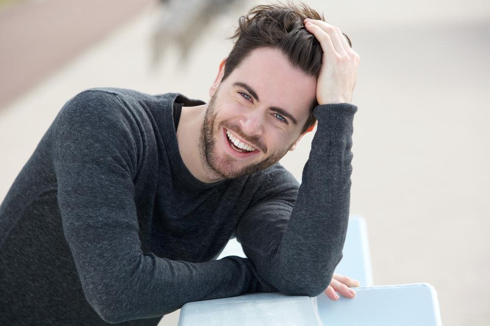 man smiling outdoors without forehead wrinkles men