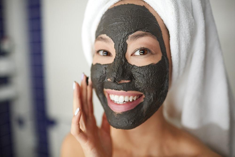 smiling woman applying a magnetic face mask with her fingers