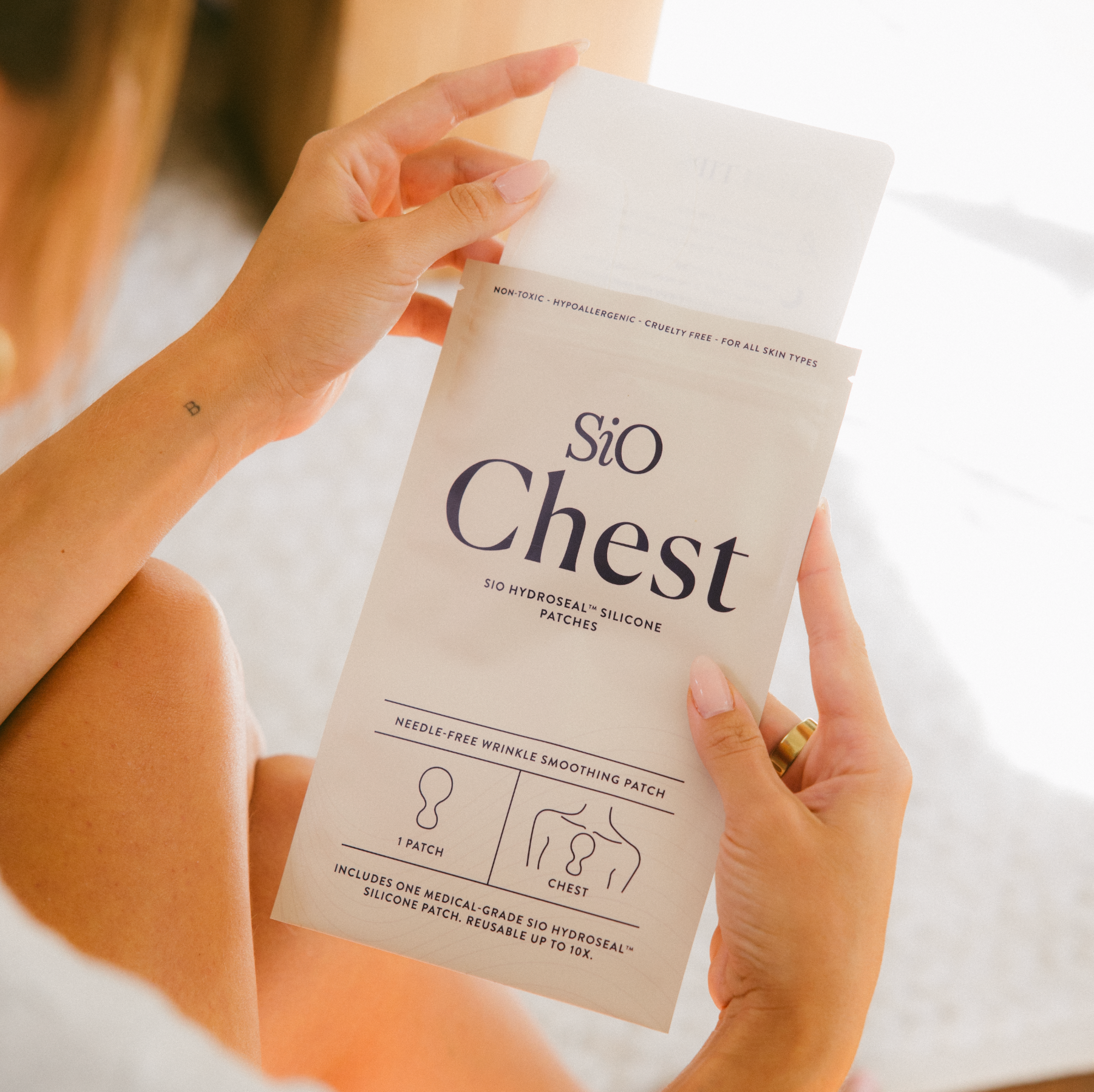 Person holding a package of 'Sio Chest' patches with a blurred background
