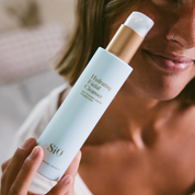 Person holding a 'Hydrating Facial Cleanser' by SiO with a blurred background