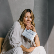 Woman holding a package labeled 'Eye & Smile' against a gray background