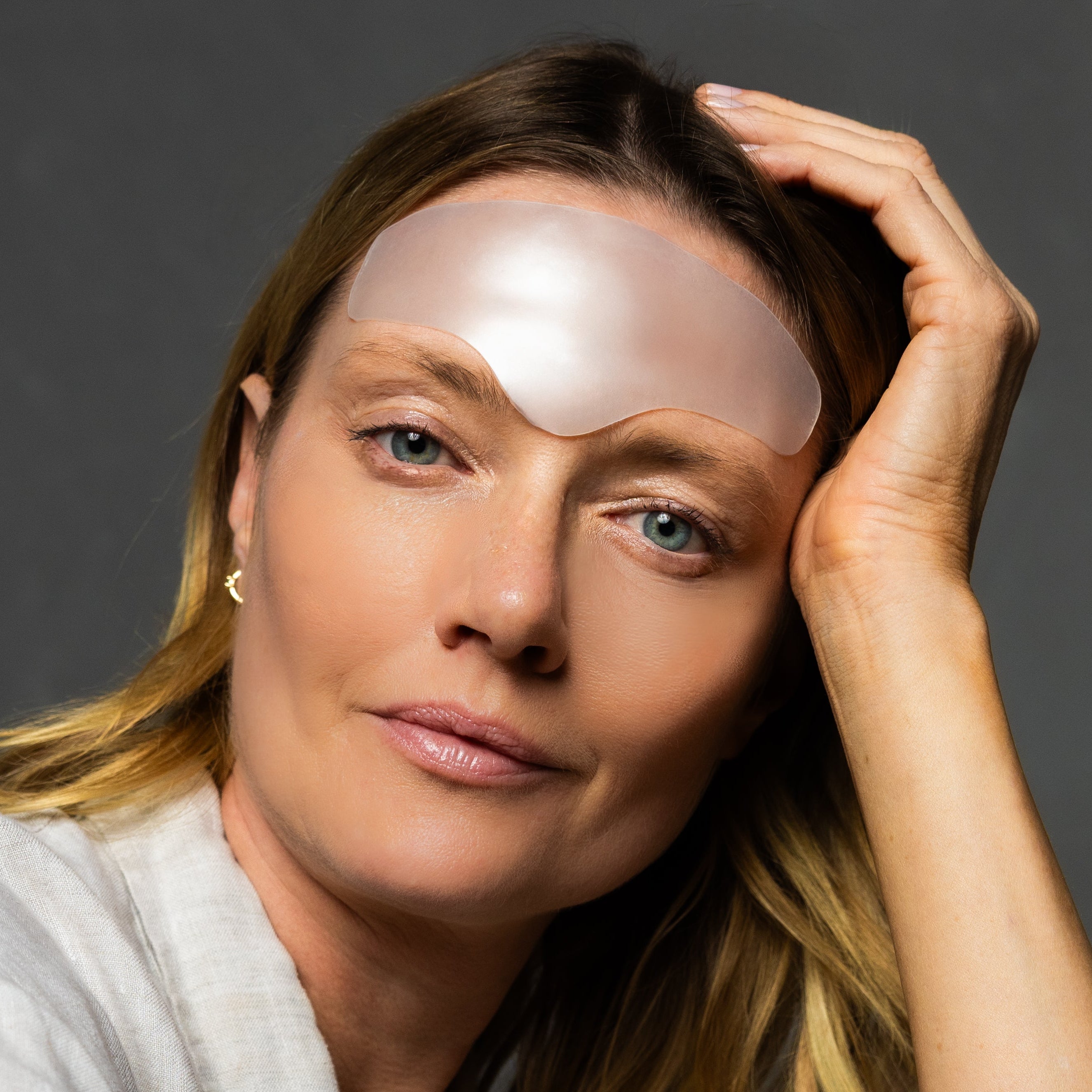Woman wearing a satin eye mask with a gray background