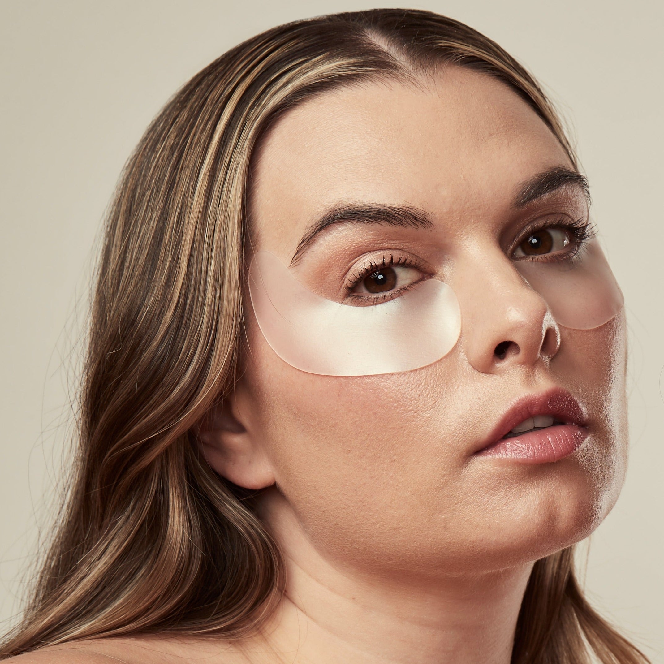 woman wearing eye patches against a neutral background